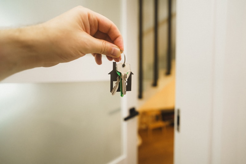 A hand holding house keys in a bright doorway