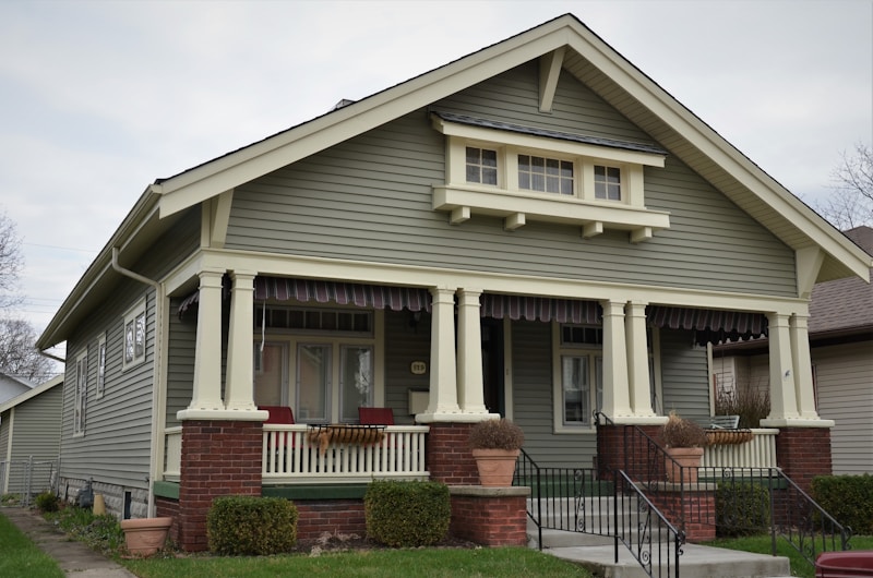 A green Craftsman bungalow in Pasadena with a deep porch and brick piers