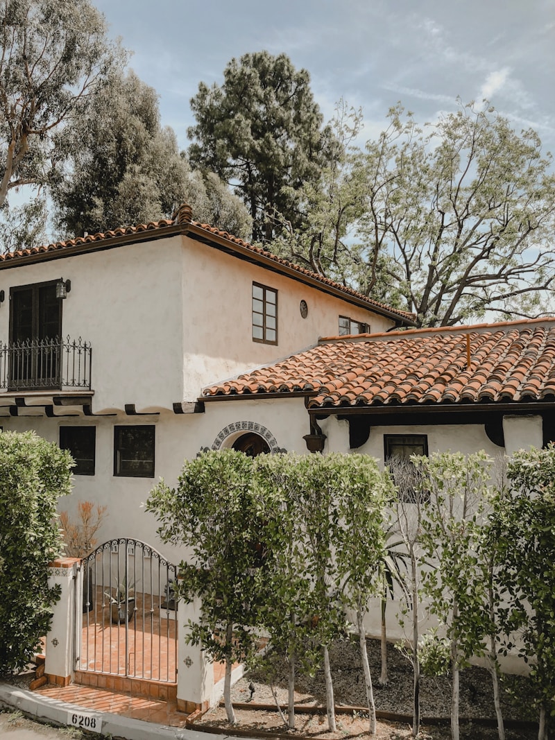 A Spanish Colonial Revival home with white stucco, clay tile roof, and an arched entry