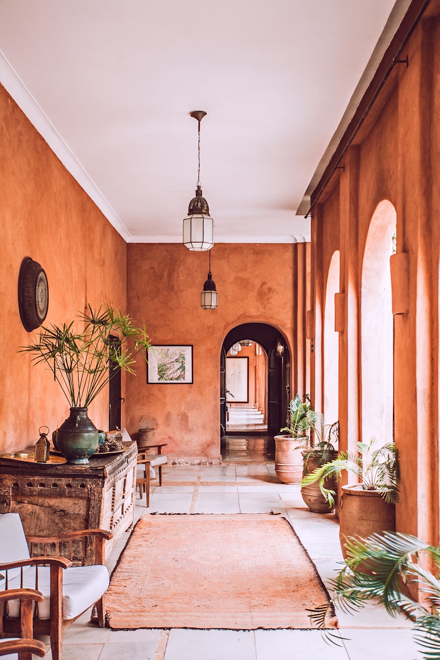A Spanish revival hallway with terracotta plaster walls, arches, and antique furnishings